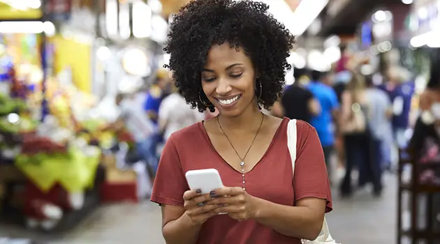 african american woman looking at cell phone in outdoor market